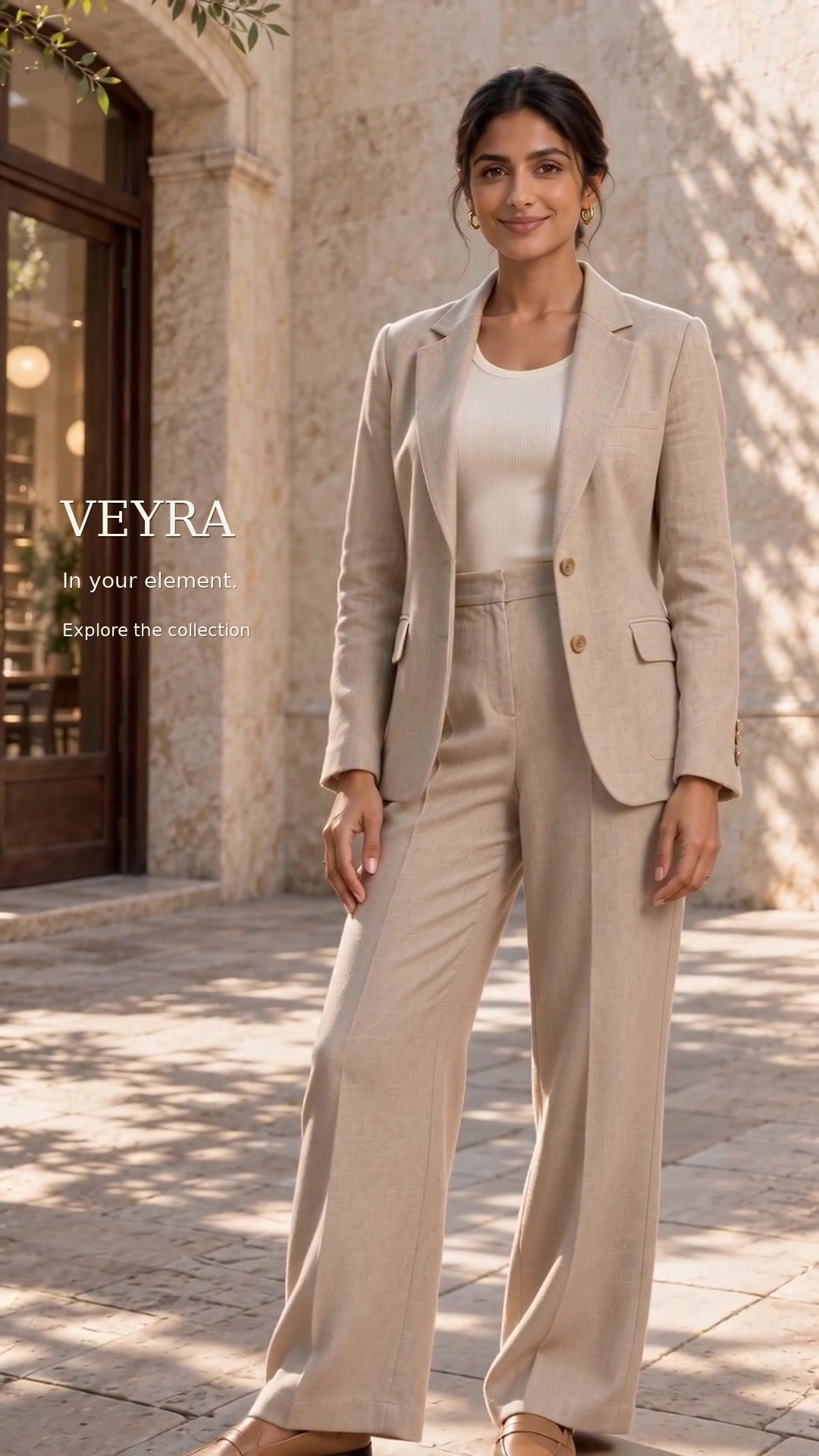 A model in a tailored beige suit moves through a sunlit courtyard in the VEYRA lifestyle video